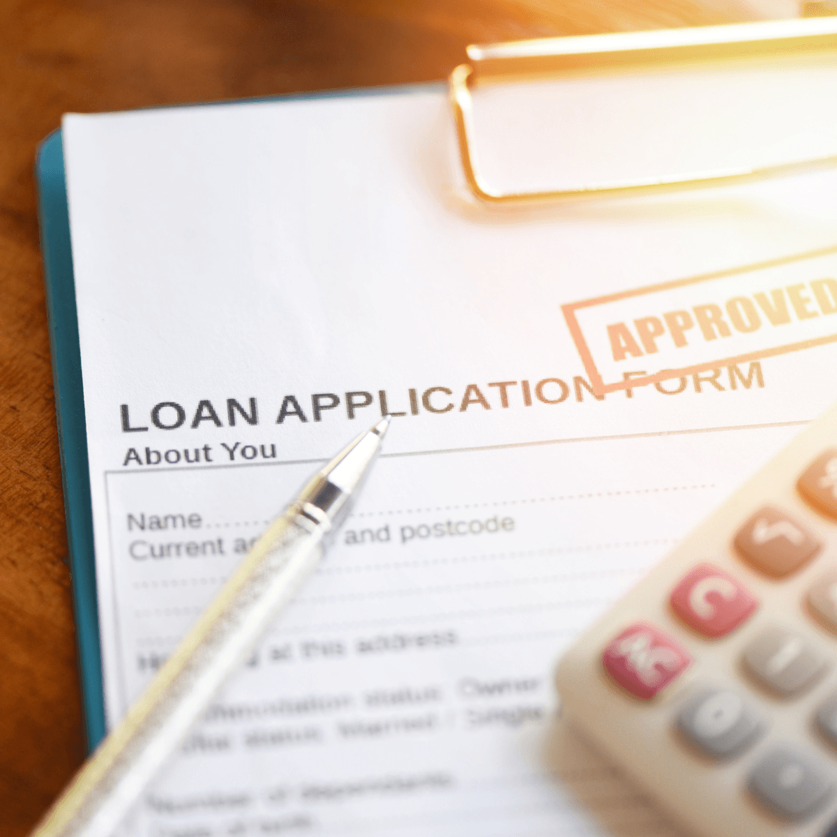  Loan application form stamped approved, with a pen and calculator on top.