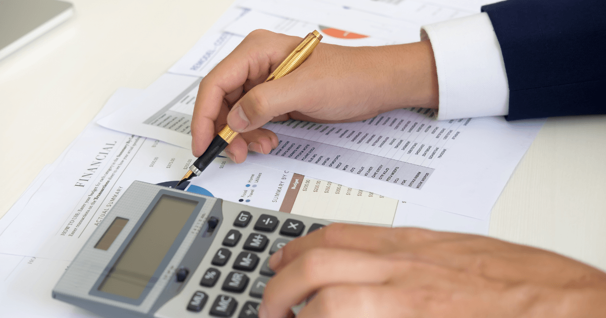 Hands using a calculator while reviewing financial summary documents