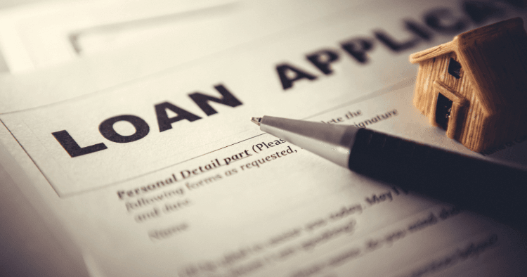 Loan application form with pen and small house model representing an equity mortgage for property improvement