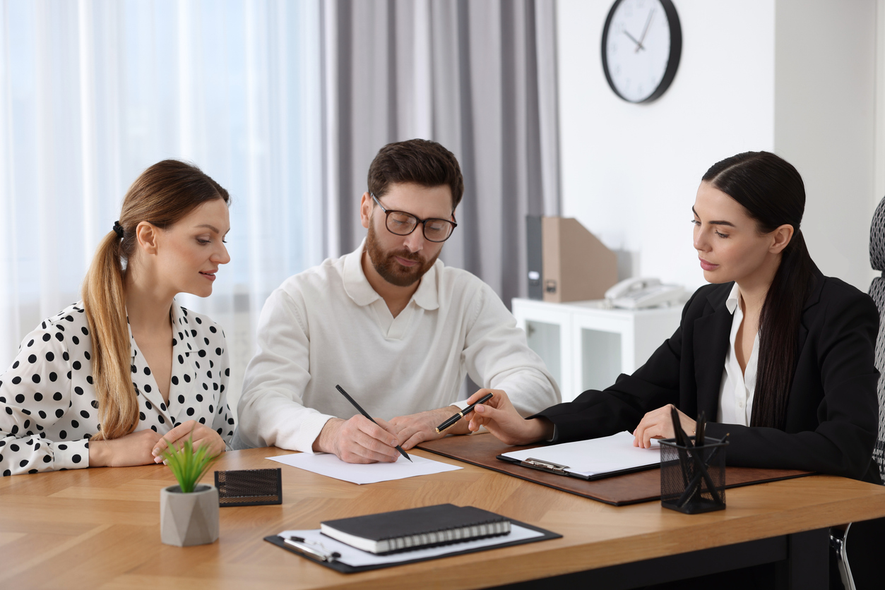 Couple signing mortgage documents with financial advisor in office