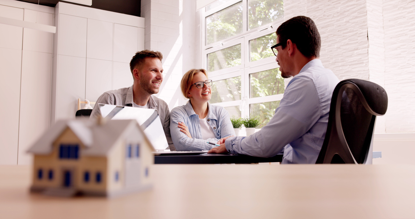 Couple discussing home financing options with mortgage advisor in office