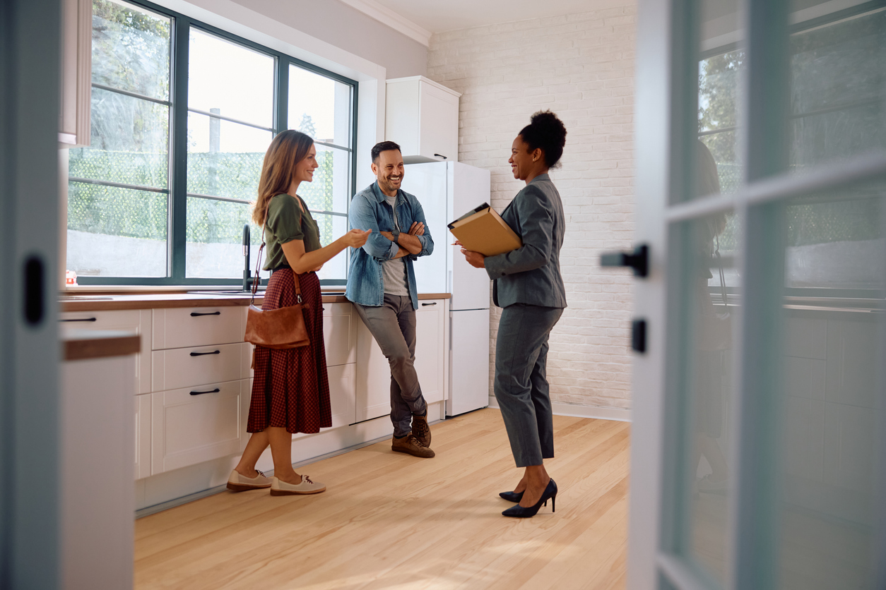 Couple talking with real estate agent while viewing a modern kitchen
