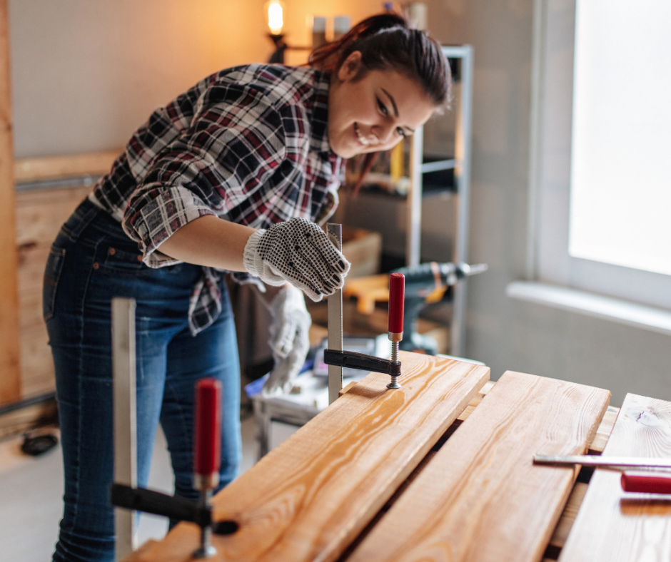 Woman applying stain or finish to wooden boards during home renovation project