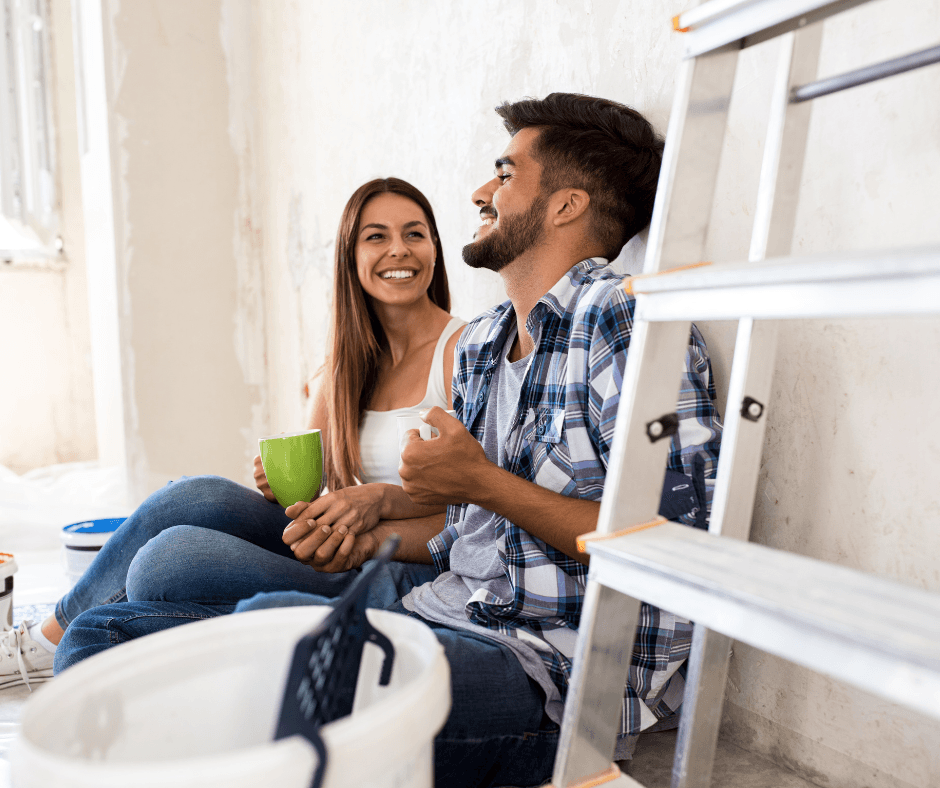 Couple relaxing together during home renovation, sitting among construction materials and tools