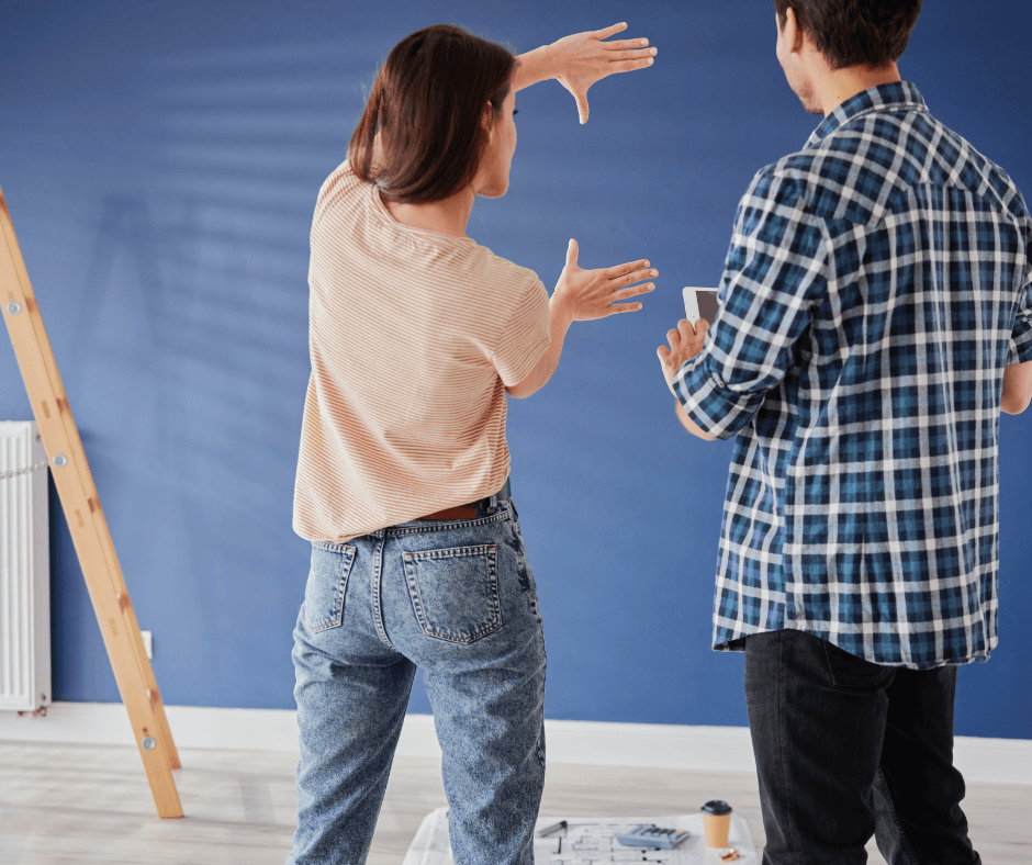 Couple visualizing room layout while standing in front of freshly painted blue wall during home renovation